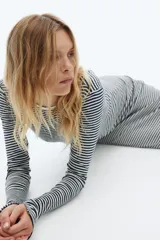 Vestido midi de punto acanalado a rayas horizontales blancas y negras, de manga larga, corte ajustado, escote redondo y espalda en U. Tiene tajo lateral.