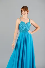 Vestido largo de fiesta color turquesa, con cuerpo tipo corset bordado con lentejuelas y transparencias, tirantes finos y falda fluida con tajo lateral.