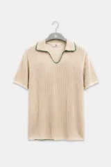 Polo de manga corta color crema de tejido calado, con cuello y escote en V con bordes en hilo verde oscuro. Confeccionada en algodón.
