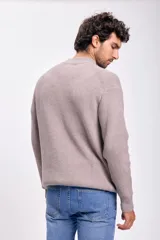 Buzo de tejido de punto color topo, con cuello simulando un cuello tortuga o mock neck, y manga larga. Presenta un tejido acanalado verticalmente.