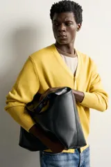 Bolso tipo shopper color negro con diseño liso, asa de hombro y compartimento principal con cierre de cremallera.