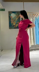 Vestido largo de fiesta color magenta, con escote estilo bardot que deja los hombros al descubierto, ajuste entallado en la cintura y falda con tajo frontal profundo.