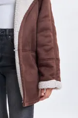 Chaqueta de abrigo color marrón con interior y solapas forradas en sherpa color crema. Presenta diseño de corte recto, mangas largas con puños de sherpa y bolsillos laterales.