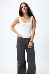 Pantalón jean ancho color gris oscuro, con elástico en la cintura, cordones ajustables en los bajos y grandes bolsillos laterales y traseros.