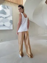 Pantalón de corte holgado y tiro medio, confeccionado en tejido brillante color dorado con acabado metalizado. Presenta cintura elástica con cordón ajustable y bolsillos laterales.