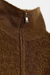 Chaqueta estilo bomber de lana bouclé color marrón, con cuello alto, cierre frontal con cremallera y puños y ruedo en tejido rib.