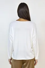 Buzo de lanilla color blanco, con cuello redondo, mangas largas y corte holgado.