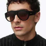 Lentes de sol estilo aviador con montura oversized de color negro y lentes polarizados en tono marrón. Presentan un diseño retro de líneas limpias y estructura robusta.