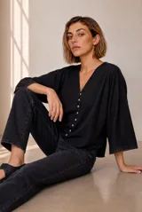 Camisa blanca de lino, con escote en V, mangas tres cuartos con detalles de encaje en los puños, cierre frontal de botones y diseño más largo en la parte trasera.