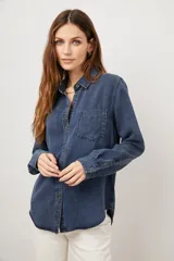 Camisa de jean azul oscuro, de corte recto, con cuello clásico, manga larga y bolsillo en el pecho.