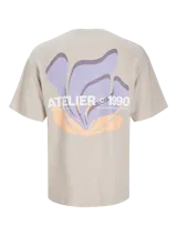 Remera beige de manga corta y cuello redondo con estampado en la espalda con la inscripción "Atelier © 1990" y un diseño abstracto en tonos lila y naranja.