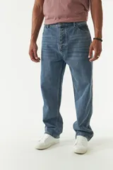 Jean de corte baggy con tiro medio, diseño amplio en piernas y cadera, con cierre y botón frontal.