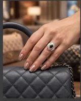 Anillo de plata 925 con diseño floral calado, engastado con una piedra central ovalada de circonia negra y pequeñas circonias blancas alrededor.