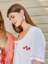 Aros con diseño de flor de pétalos blancos y centro con textura, estilo colgante.