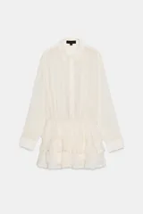 Vestido mono corto de gasa color crudo, con cuello solapa, cierre frontal de botones y manga larga con puños. Presenta cintura elástica y falda con diseño de volantes superpuestos en el bajo.