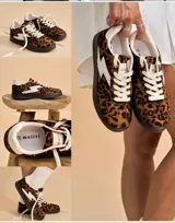 Zapatillas con estampado animal print de leopardo en tonos marrones y negros, con plataforma negra. Presentan un detalle lateral en forma de rayo blanco y cordones blancos.