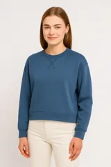 Buzo azul de corte holgado con cuello redondo y detalle de costura en forma de equis en el frente.