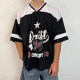 Camiseta estilo fútbol americano de corte oversize, color negro con detalles en blanco y bordó en el cuello y mangas. Presenta un estampado frontal con tipografía desgastada, una estrella y un escudo.