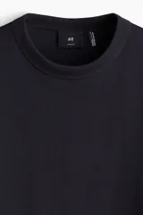 Remera negra de corte holgado, con cuello redondo ribeteado, hombros caídos y bajo recto. Confeccionada con tejido funcional COOLMAX®, una fibra de poliéster de secado rápido que elimina la humedad y regula la temperatura corporal.