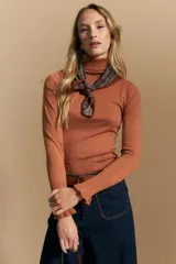 Polera de tejido fino color negro, con cuello alto y mangas largas con terminación sutilmente fruncida. Diseño ajustado al cuerpo.