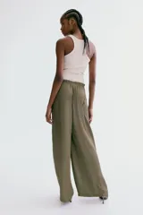 Pantalón de corte holgado en tejido fluido de satén verde militar, de piernas amplias, con bolsillos laterales discretos y cintura elástica con cordón ajustable y ribete de volado.