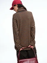 Polera de tejido de punto con diseño de rayas horizontales en tonos marrón y negro, cuello alto, mangas largas con hombros caídos y corte holgado.