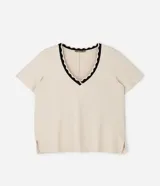 Blusa de manga corta confeccionada en viscolycra, con escote en V y detalle de cuello con borde ondulado en contraste. Presenta un diseño amplio con aberturas laterales en el ruedo.