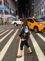 Cartera de mano tipo clutch, de cuero trenzado a mano en color negro y beige, con diseño de rayas verticales.