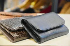 Billetera de cuero marrón con estampado de piel de serpiente, con cierre de broche a presión.