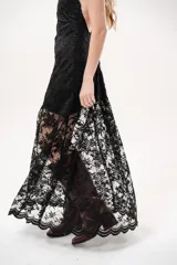 Vestido largo negro de encaje con cuello halter y espalda descubierta, con forro corto y falda translúcida.
