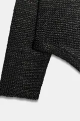 Jersey de punto color negro con cuello redondo y manga larga, de diseño amplio y bajo asimétrico.