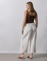 Pantalón de lino color crudo, de corte ancho y largo cropped, con bolsillos laterales.