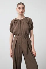 Pantalón baggy negro de silueta relajada con volumen amplio y caída fluida. Presenta detalles de ajuste con hebillas metálicas en el bajo y un cinturón de tela con hebilla metálica en la cintura.