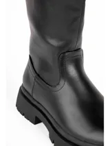 Bota alta de cuero sintético negro, con suela track gruesa y tacón bajo cuadrado.