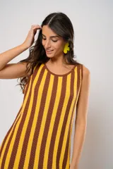 Vestido corto tejido a rayas verticales color amarillo y marrón, con escote redondo y mangas sisa. Incluye cinturón marrón con hebilla dorada.