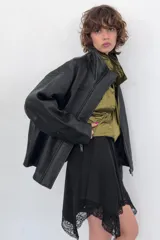 Cazadora de corte oversize confeccionada en 100% piel. Presenta cuello subido, manga larga con hombro caído y cierre frontal mediante cremallera y botones a presión ocultos bajo una solapa. Incluye bolsillos laterales ocultos en las costuras y forro interior.