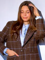 Blazer de paño de lana en color marrón con diseño de cuadros grandes en tonos claros. Presenta solapas clásicas con detalle de costura, cierre frontal con un botón y bolsillos laterales. El corte es recto y estructurado.