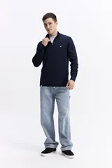 Buzo de punto con medio cierre frontal, cuello elevado y puños acanalados. Presenta un pequeño logo bordado en el pecho.