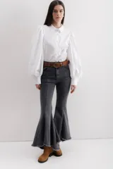 Jean elastizado azul oscuro con diseño de volados en la parte baja de la pierna, ruedo descosido con juego de largos (más largo atrás que adelante).