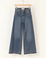 Jean de corte wide leg y tiro alto en denim azul, con costuras verticales delanteras, pespuntes marcados y ruedo desflecado.