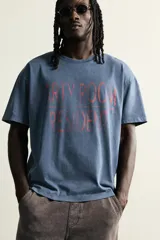 Remera de corte relaxed fit con efecto lavado, cuello redondo y manga corta. Presenta un estampado frontal de texto en tono contrastante.