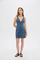 Vestido mini de jean al cuerpo, con escote en V profundo y costuras pespunteadas visibles.