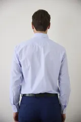 Camisa de vestir blanca de manga larga, con cuello clásico y cierre frontal de botones. Presenta un corte entallado que se adapta a la silueta.