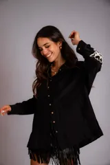 Camisa beige de corte amplio, con cuello clásico, cierre frontal con botones, mangas largas con puños abotonados y bordado floral en las mangas.