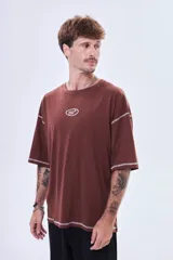 Remera negra de corte boxy con costuras a la vista en color blanco. Presenta un pequeño logo bordado en el centro del pecho y mangas cortas amplias.