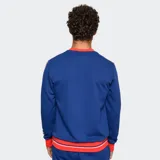 Buzo de cuello redondo color azul, con detalles en rojo y blanco en cuello, puños y ruedo. Presenta el escudo del Club Nacional de Football en el pecho y bandas laterales con diseño deportivo en las mangas.