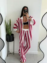 Conjunto de dos piezas tejido a crochet con diseño de rayas verticales en color fucsia y blanco. Incluye una camisa de manga tres cuartos con cuello camisero y un pantalón de corte recto con cintura elástica.