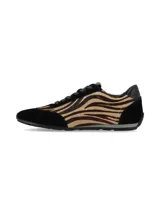 Sneaker de mujer con diseño de animal print tipo cebra en tonos marrón y negro, combinada con paneles de gamuza negra en la puntera, talón y laterales. Presenta cordones negros y una suela plana de perfil bajo.