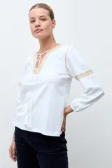 Remera de estilo boho color blanco, con mangas largas, escote en V con cordones y detalle de bordado en el pecho.