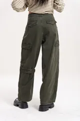 Pantalón cargo de tiro medio-alto en color verde oliva, con diseño holgado, múltiples cierres decorativos y funcionales, y bolsillos laterales.